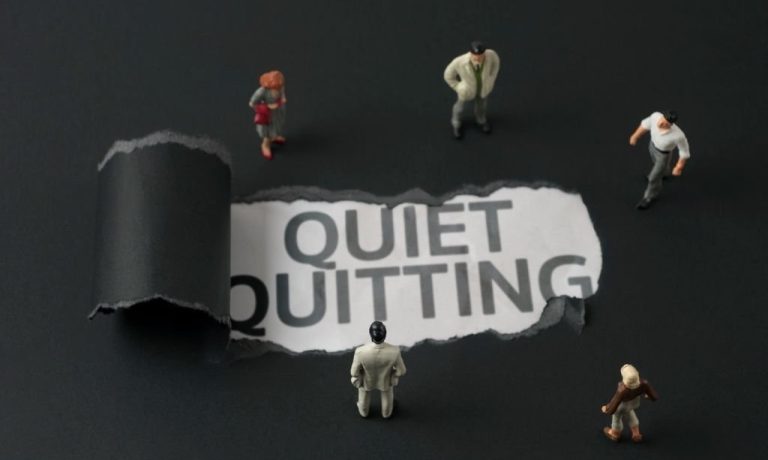 .quiet quitting' written below the torn page with employee figures standing around
